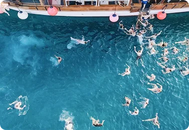Guests swimming in open water beside the boat