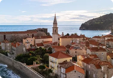 Budva old town's red roofs and church tower above the sea