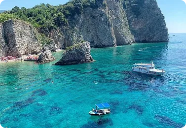 Boats anchored over turquoise water beside rocky cliffs